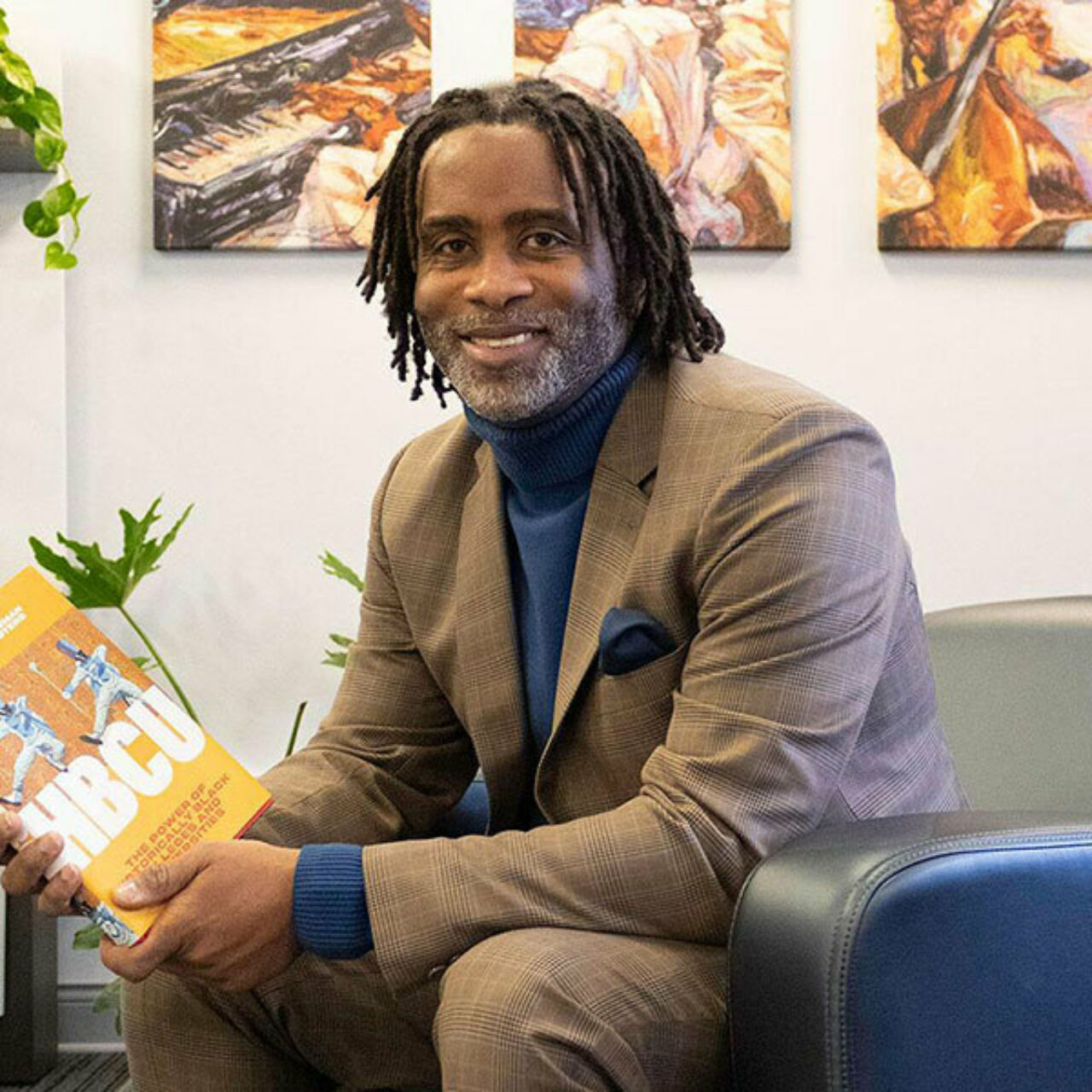 Dean Esters seated and holding a book on HBCU, which he co-wrote.