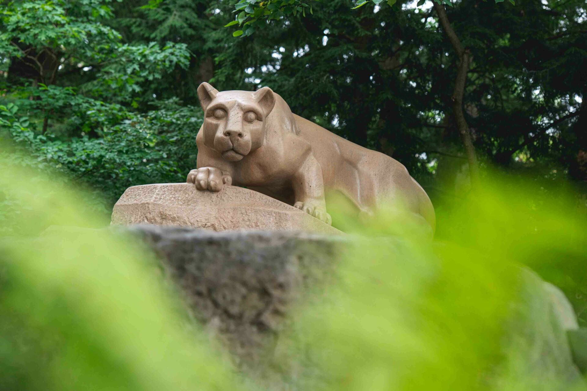 The Nittany Lion Shrine through green leaves