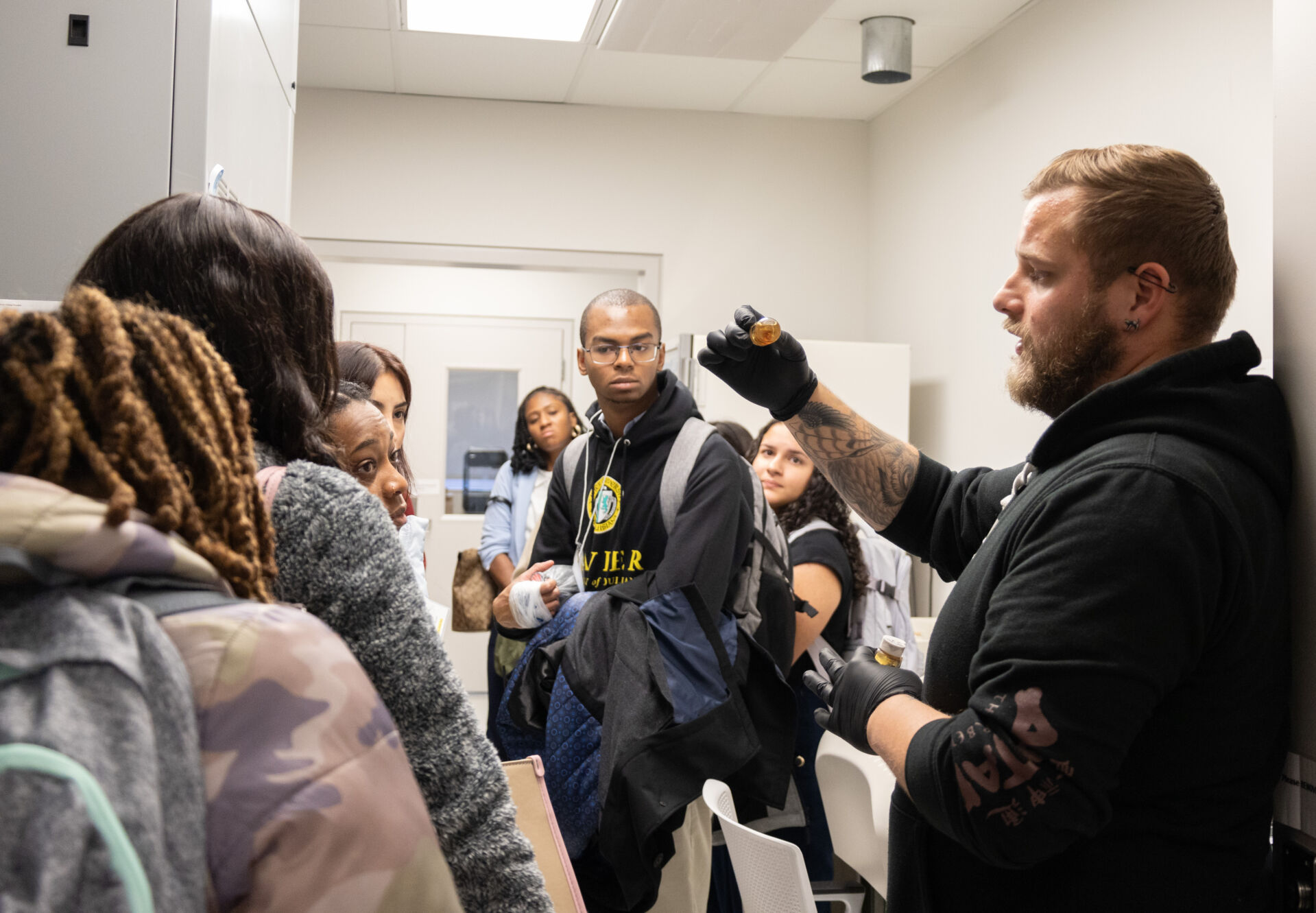 Students admiring a tour guide showing them a beaker with fluid in the lab